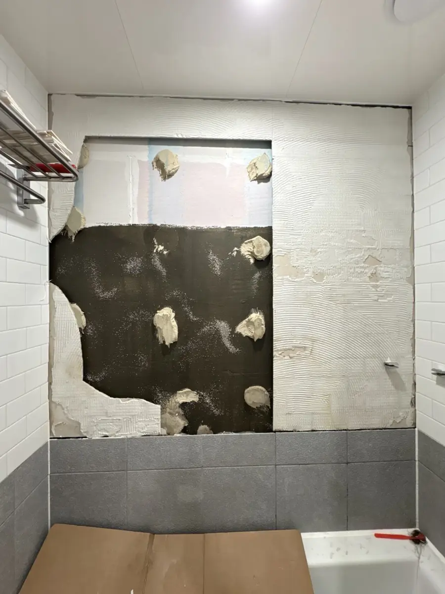화장실 바닥 타일 시공 관련 서비스, 화장실 타일 교체 안내 — 벽 타일 일부를 철거해 접착면이 드러난 욕실 벽